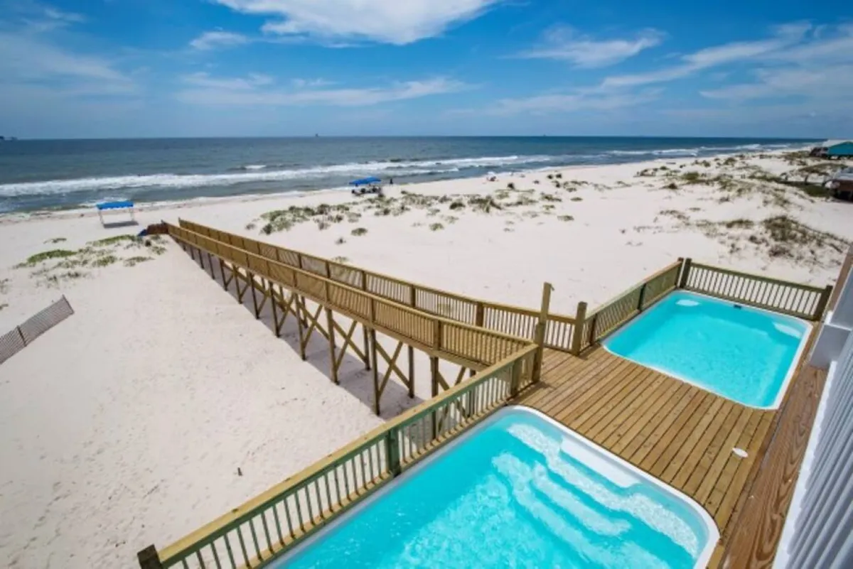 An inviting exterior shot showing the beachfront, boardwalk, pools, and a wide expanse of ocean view. The scene conveys a joyful, communal atmosphere and visually represents the variety of activities and backdrop available to guests during their stay.